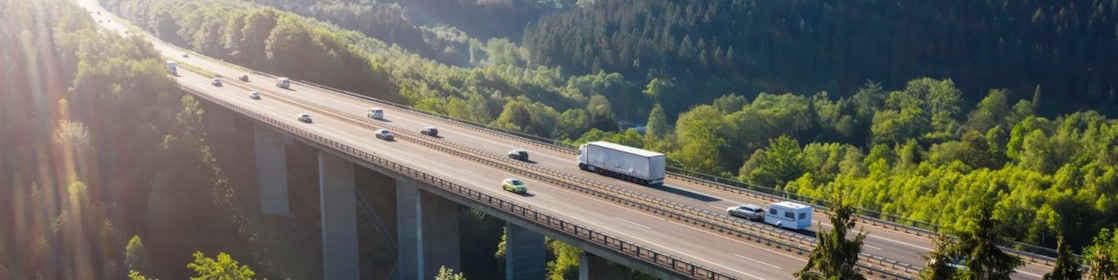 Vehicule care traversează un viaduct într-un peisaj natural frumos