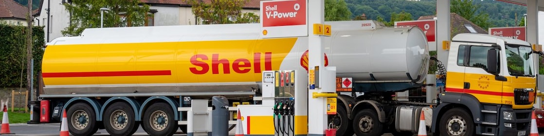 Cisternă Shell care alimentează la o stație de alimentare situată într-o zonă rurală plină de verdeață