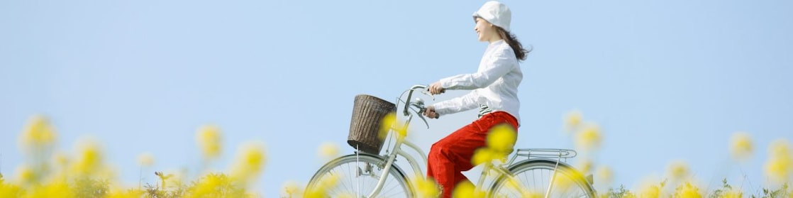 O tânără merge pe bicicletă printr-un câmp cu flori de vară