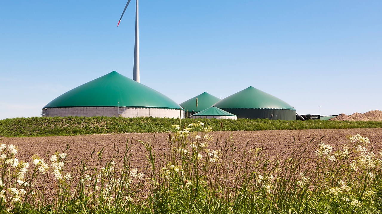 Clădiri rotunde care formează o fabrică de biogaz, alături de o instalație eoliană