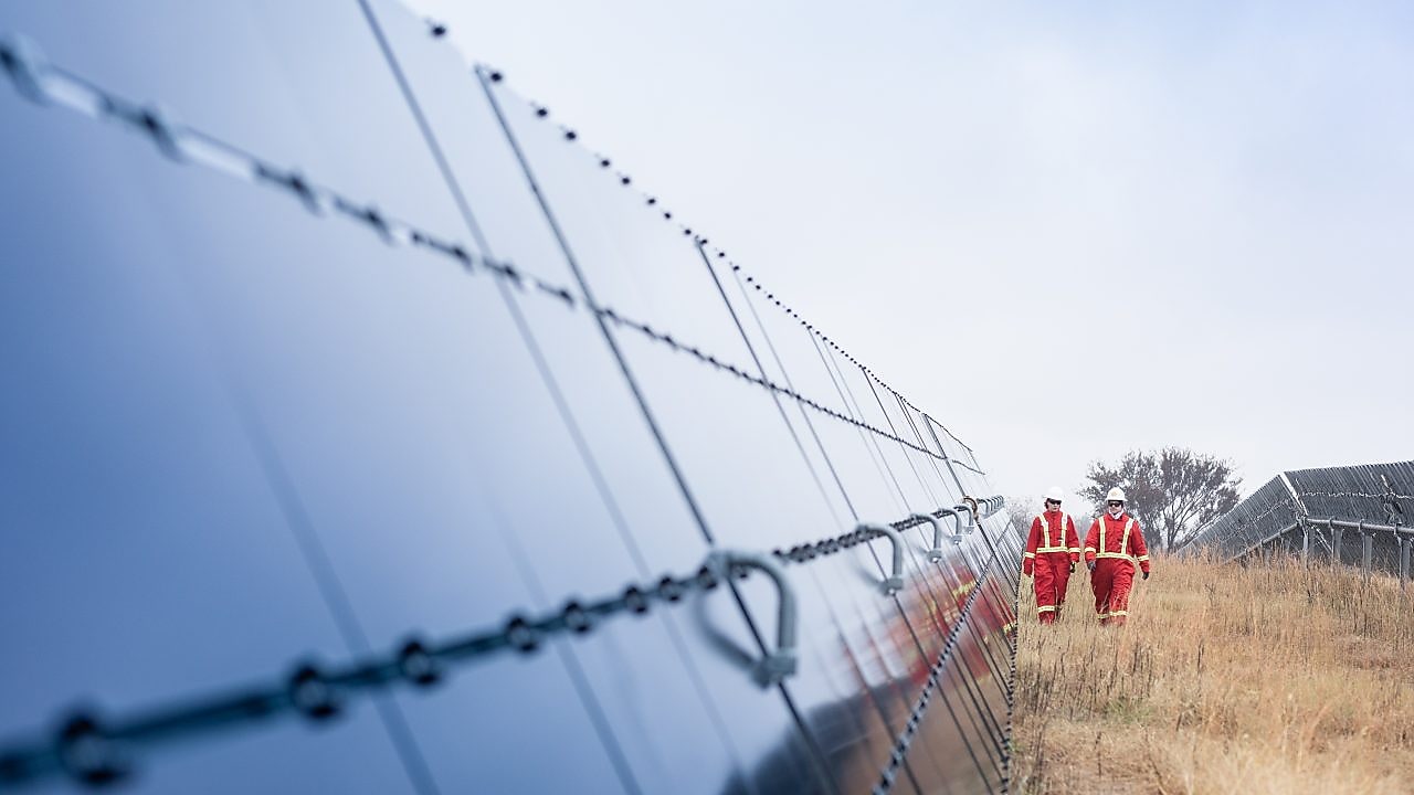 Doi angajați Shell mergând printre panouri solare masive