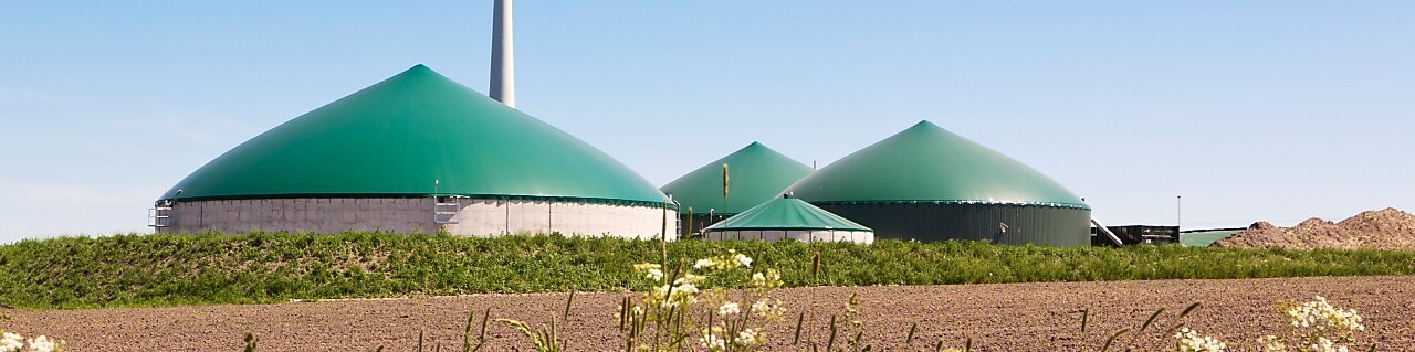 Clădiri rotunde care formează o fabrică de biogaz, alături de o instalație eoliană