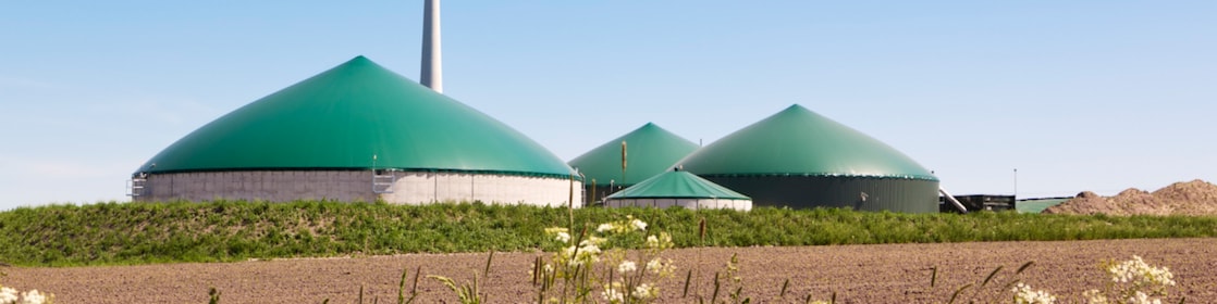 Clădiri rotunde care formează o fabrică de biogaz, alături de o instalație eoliană