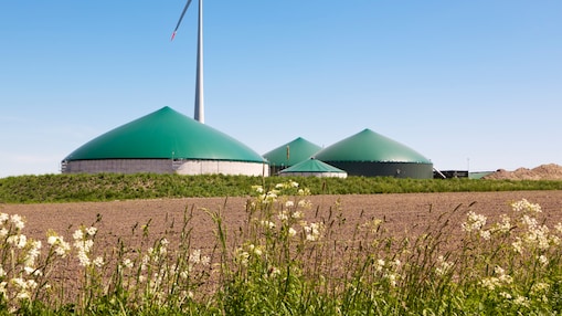 Clădiri rotunde care formează o fabrică de biogaz, alături de o instalație eoliană