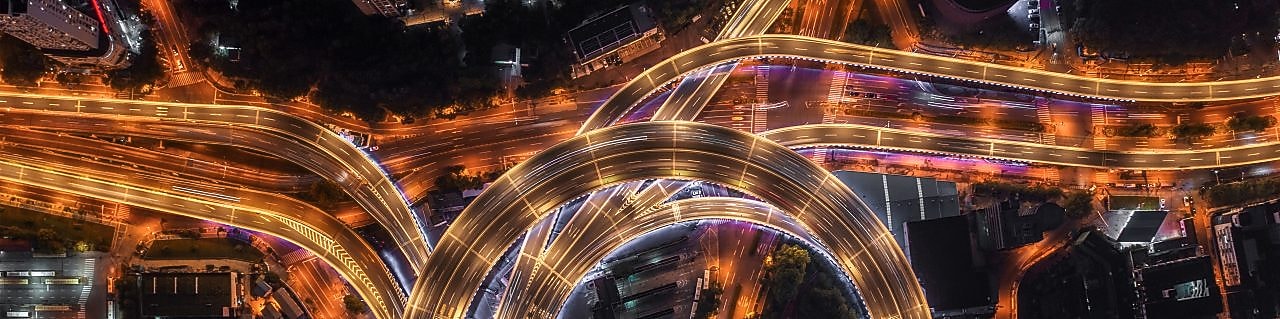 Nod rutier circular cu autostrăzi suprapuse și iluminate artificial, văzut de sus, noaptea.