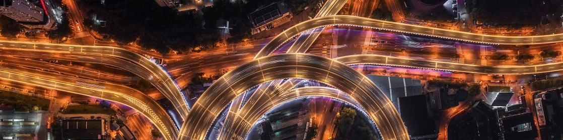 Nod rutier circular cu autostrăzi suprapuse și iluminate artificial, văzut de sus, noaptea.