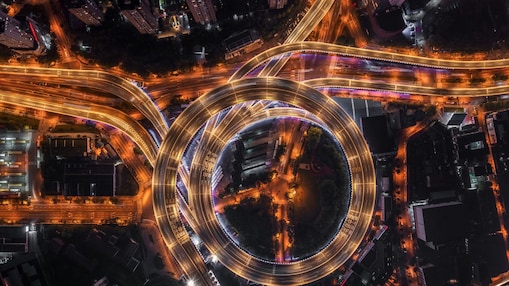 Nod rutier circular cu autostrăzi suprapuse și iluminate artificial, văzut de sus, noaptea.