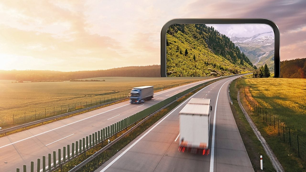 Două camioane care se întâlnesc, în mișcare, pe sensurile opuse ale unei autostrăzi. Șoseaua este într-o zonă plană, dar în planul doi se găsește un portal sugerat grafic care continuă drumul într-o zonă alpină.