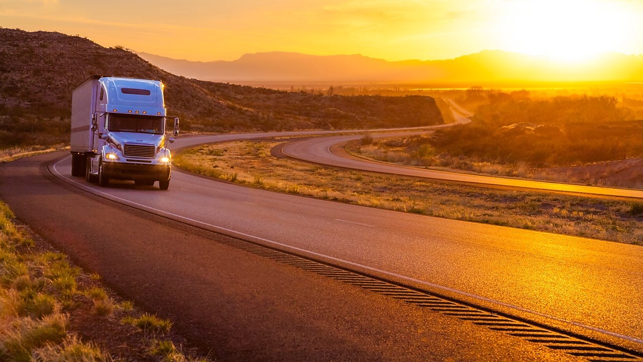 Camion cu 18 roți pe o șosea interstatală la apusul soarelui