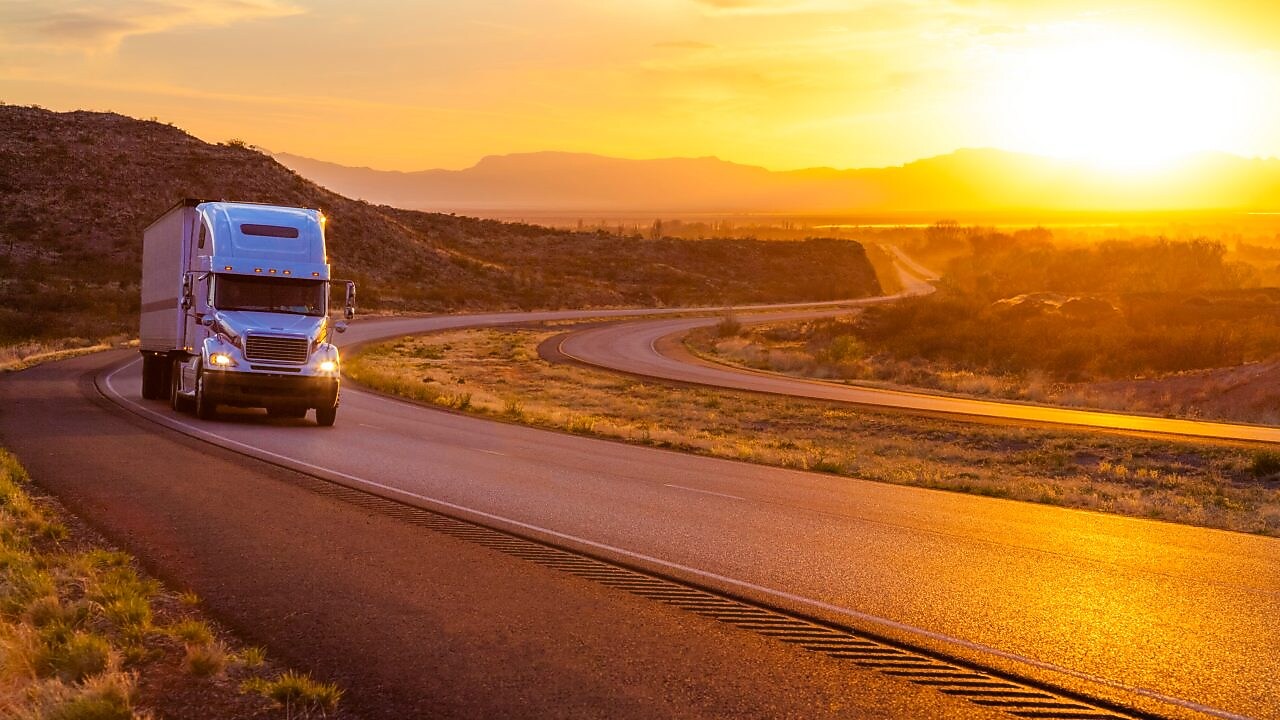 Camion cu 18 roți pe o șosea interstatală la apusul soarelui