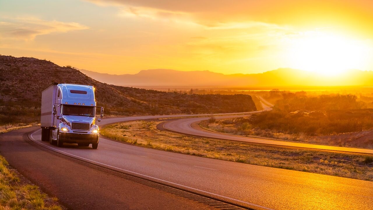 Camion cu 18 roți pe o șosea interstatală la apusul soarelui