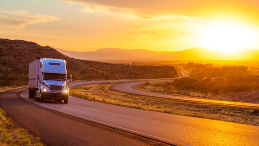 Camion cu 18 roți pe o șosea interstatală la apusul soarelui