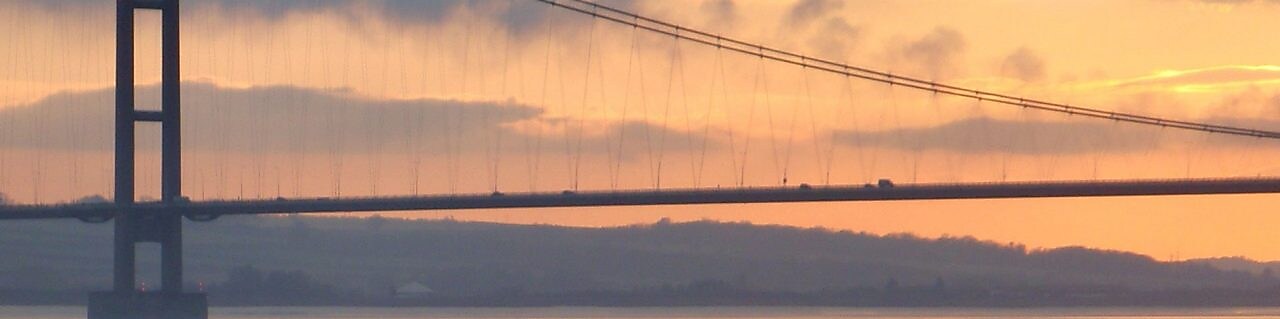 pod suspendat peste fluviu la apus de soare